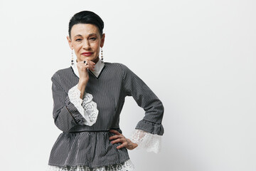 Portrait of an elegant older woman in gray shirt and white skirt posing confidently for camera