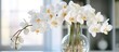 A glass vase filled with white orchid flowers sits elegantly on top of a table, adding a touch of natural beauty to the rooms decor.