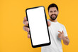 © New Africa - Happy man holding smartphone with empty screen on orange background