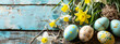 An arrangement of painted Easter eggs tied with twine and daffodils on a rustic wooden surface symbolizing spring and renewal