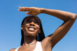 © Artem Podrez/Stocksy - Portrait of a female athlete with dreadlocks on a blue sky background