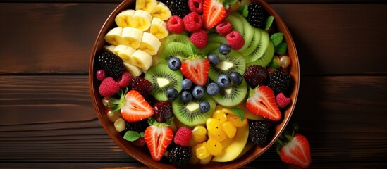 Poster - A top-down view of a bowl filled with a variety of different types of fruits, creating a colorful and appetizing display. The fruits are neatly arranged and ready to be enjoyed as a fresh and