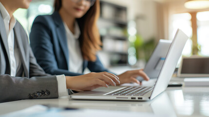 Poster - Two women are sitting at a table with a laptop open in front of them. They are both dressed in business attire and appear to be working on a project. Business concept. Generative ai illustration.