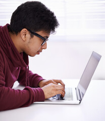 Wall Mural - Man, focus and typing with laptop for research, development or creative startup on table at office desk. Male person, nerd or young geek with vision on computer for email, networking or communication