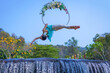 Beautiful Asian girl performing show aerial hoop or aerial ring in various positions and spinning stunts on the blue sky.