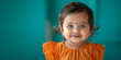 Small cute smiling indian girl with bindi over teal background. Banner with copy space. Shallow depth of field.