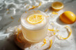 limoncello and Prosecco cocktail with lemon zests on light marble plate with a lemon slice
