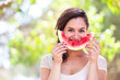 Beautiful young woman at park eating a slice of watermelon