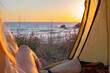 woman legs stick out from a tent at dawn on the sea coast. Camping. Travel and tourism