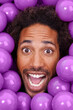 © peopleimages.com - Ball pit, excited and portrait of black man with plastic toys for fun, playful and happy on background. Surprise, facial expression and face of person with purple balls, decoration and objects