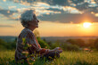Elderly woman meditating on a hill at sunset in summer