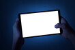 A teenager holds a tablet with two hands at night. Phone with white screen on defocused dark blue background. There is a work path in the file.