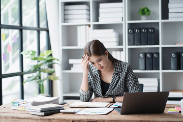 Poster - A woman is sitting at a desk with a laptop and a book