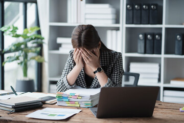 Poster - A woman is sitting at a desk with a laptop and a stack of papers
