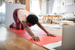 © Davor - Woman stretching on yoga mat with laptop at home