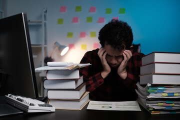 Poster - A man is sitting at a desk with a computer and stacks of books