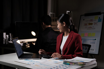 Poster - A woman in a red jacket is sitting at a desk with a laptop and a calculator