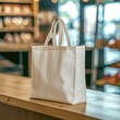 A plain canvas tote bag on a wooden counter with a blurred cafe background