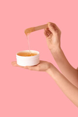 Sticker - Female hands holding container with sugaring paste and spatula on pink background