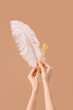 © Pixel-Shot - Female hands holding spatula with sugaring paste and feather on brown background