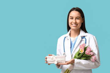 Canvas Print - Female doctor with pink tulips and gift box on blue background. Women's Day celebration