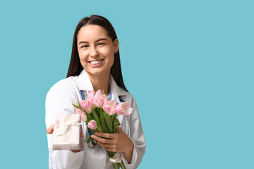 Canvas Print - Female doctor with pink tulips and gift box on blue background. Women's Day celebration