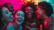 Group of joyful young people laughing in neon light. Vibrant party and fun concept