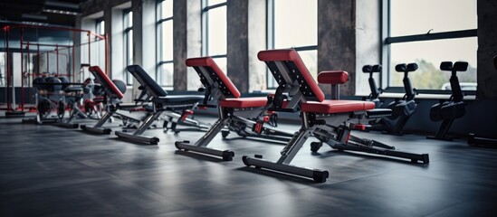 A row of various gym equipment such as treadmills, weight benches, and elliptical machines lined up in a bright and spacious gym.