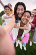 © CarlosBarquero - Vertical. Multirracial group of young friends taking selfie picture in piggyback in the park hugging by couples. Happy millennial people smiling together looking at camera outside. University students
