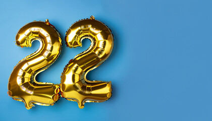Wall Mural - Banner with number 22 golden balloon with copy space. twenty two years anniversary celebration concept on a blue background.