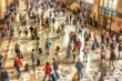 A tilt-shift view of passengers with suitcases traversing a spacious airport terminal.