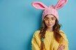 Portrait of a pretty young girl wearing bunny ears isolated over blue background