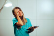 © nicoletaionescu - Stressed Medical Doctor Holding a Tablet Pc Feeling Overwhelmed. Stressed health care worker feeling overworked and overbooked.