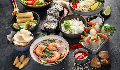 Sticker - Traditional Asian food table. Spring roll, rice, shrimp, sushi, vegetables, meat on dark background