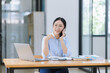 © SOMKID - Asian accounting woman using smartphone working with document paper and laptop computer at table office, Financial and accounting woman concept.