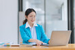 © SOMKID - Asian businesswoman wear glasses with Wear a suit working on digital laptop computer in office.