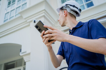 Wall Mural - A technician sets up a CCTV camera on the facade of a residential building.