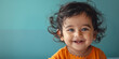 Small cute smiling indian girl with bindi over teal background. Banner with copy space. Shallow depth of field.