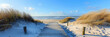 A wooden walkway leading to the beach, surrounded by dunes and grasses under a clear blue sky,