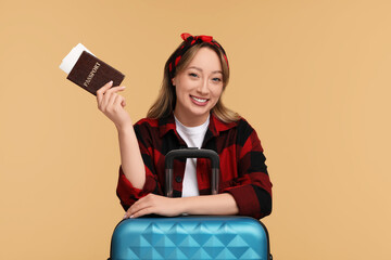 Wall Mural - Happy young woman with passport, ticket and suitcase on beige background