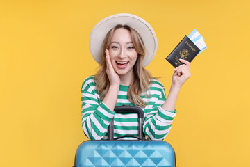 Poster - Happy young woman with passport, ticket and suitcase on yellow background