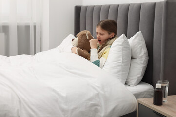 Sticker - Sick girl with teddy bear coughing on bed at home