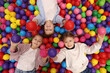 © New Africa - Happy little kids lying on many colorful balls, top view