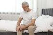 © New Africa - Arthritis symptoms. Man suffering from pain in knee on bed at home