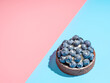 Blueberries mini tart on duotone blue and pink background with copy space. Fresh blueberry tart as summer food concept with hard shadows in bright summer light. Top view or flat lay