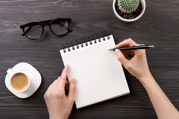 Canvas Print - Woman with notebook and pen at grey wooden table, top view. Space for text