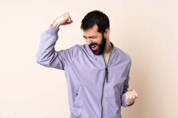 Caucasian man with beard wearing a jacket over isolated background celebrating a victory