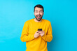 © luismolinero - Young caucasian man over isolated blue background surprised and sending a message