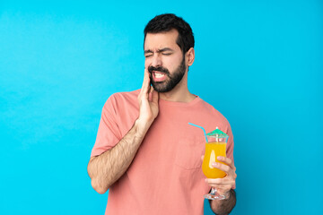 Wall Mural - Young man over holding a cocktail over isolated blue background with toothache