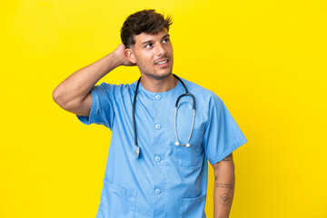 Young surgeon doctor man isolated on yellow background thinking an idea